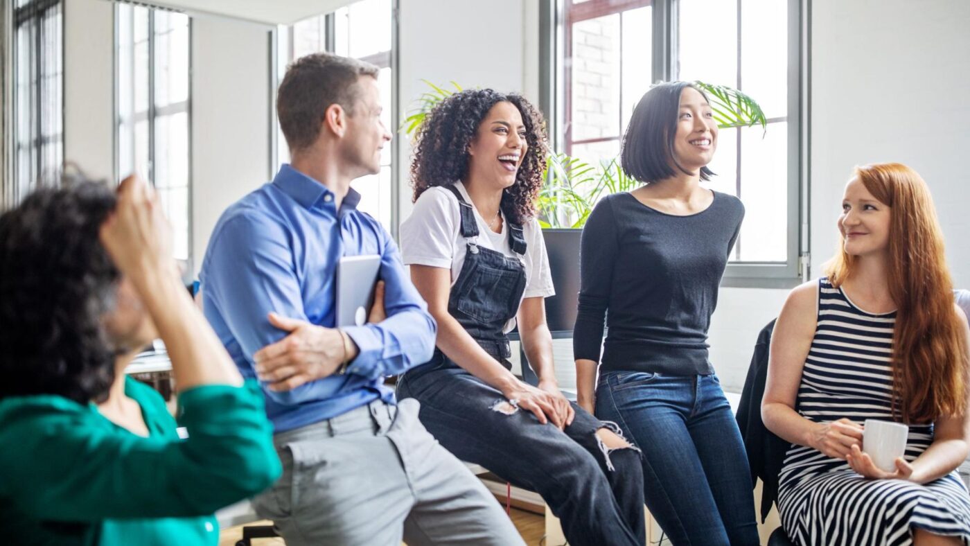 Equipo de trabajo diverso reunido en oficina moderna, ejemplo de cultura organizacional positiva y beneficios laborales en empresas