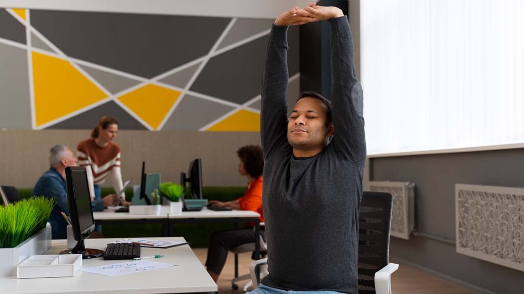 Empleado practicando mindfulness y estiramientos en oficina, bienestar laboral y transformación empresarial