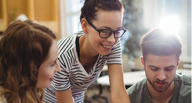 Tres personas colaboran sonrientes en una oficina mientras revisan un documento, simbolizando trabajo en equipo y planificación estratégica. Ideal para representar la creación o revisión de un checklist de beneficios laborales.