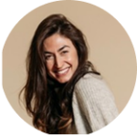 Retrato casual de perfil circular de una mujer joven con cabello largo y oscuro, sonriendo ampliamente de forma alegre, con la cabeza inclinada. Viste un cárdigan de punto gris claro sobre un fondo liso de estudio en tono beige neutro y cálido