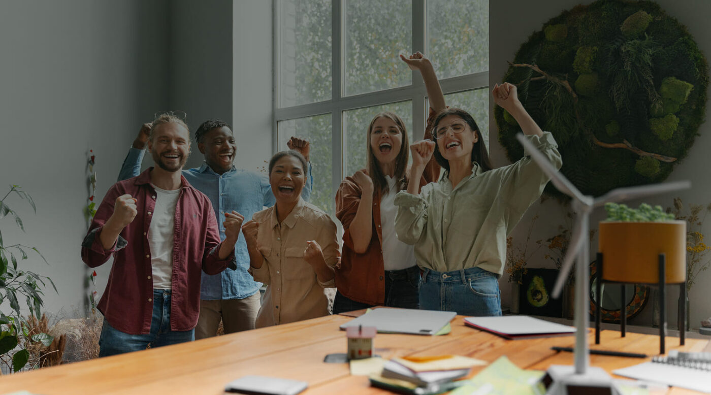 Equipo de trabajo celebrando con entusiasmo en una oficina.